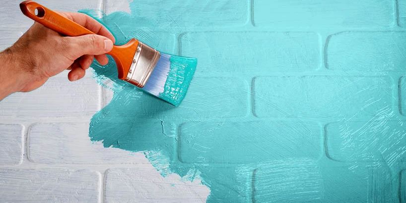 Photo of someone painting a white brick wall turquoise