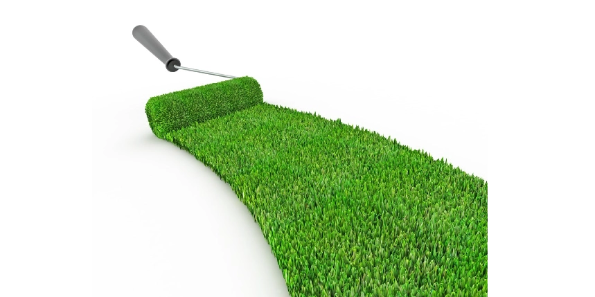Photo of a gray-handled paint roller painting green grass onto the white background