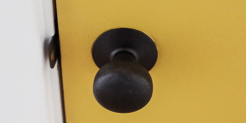 Photo of a dark doorknob on a yellow door