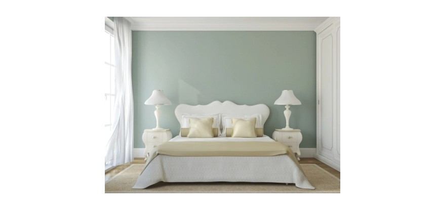 Photo of a bedroom with light colored furniture against a sage green wall
