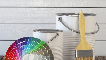 Photo of two paint cans, an unused pain brush, and a fan of paint swatches