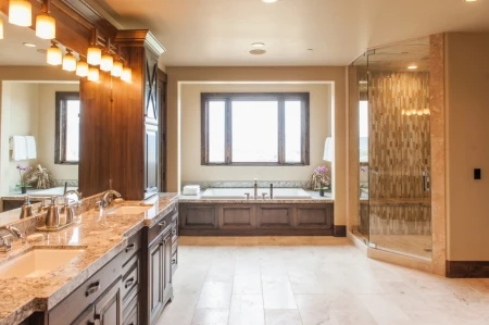 Photo of an expansive bathroom with warm colors, two sinks, a large tub, and a large shower