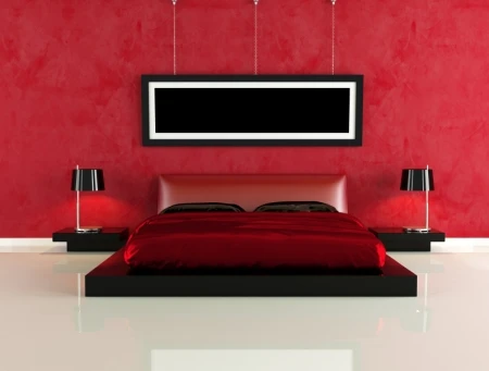 Photo of a bedroom with a red bed and red accent wall