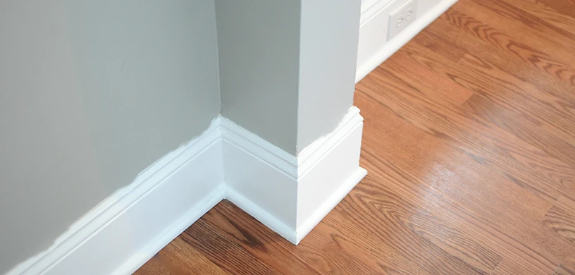 Picture of a sloppy, white paint trim against a grey wall
