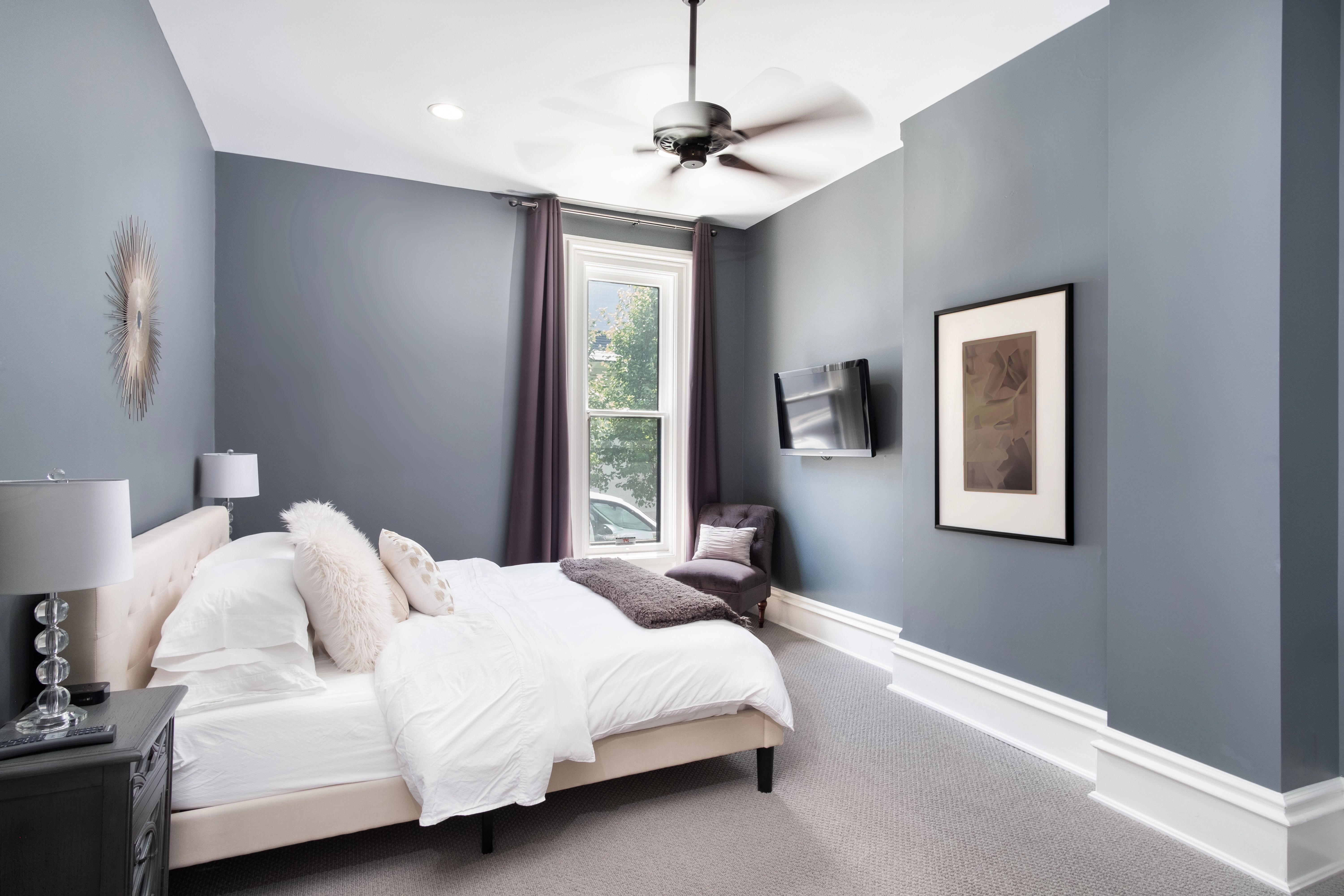 Modern chic style bedroom with steel blue walls, white trim and baseboards, and chic decor.