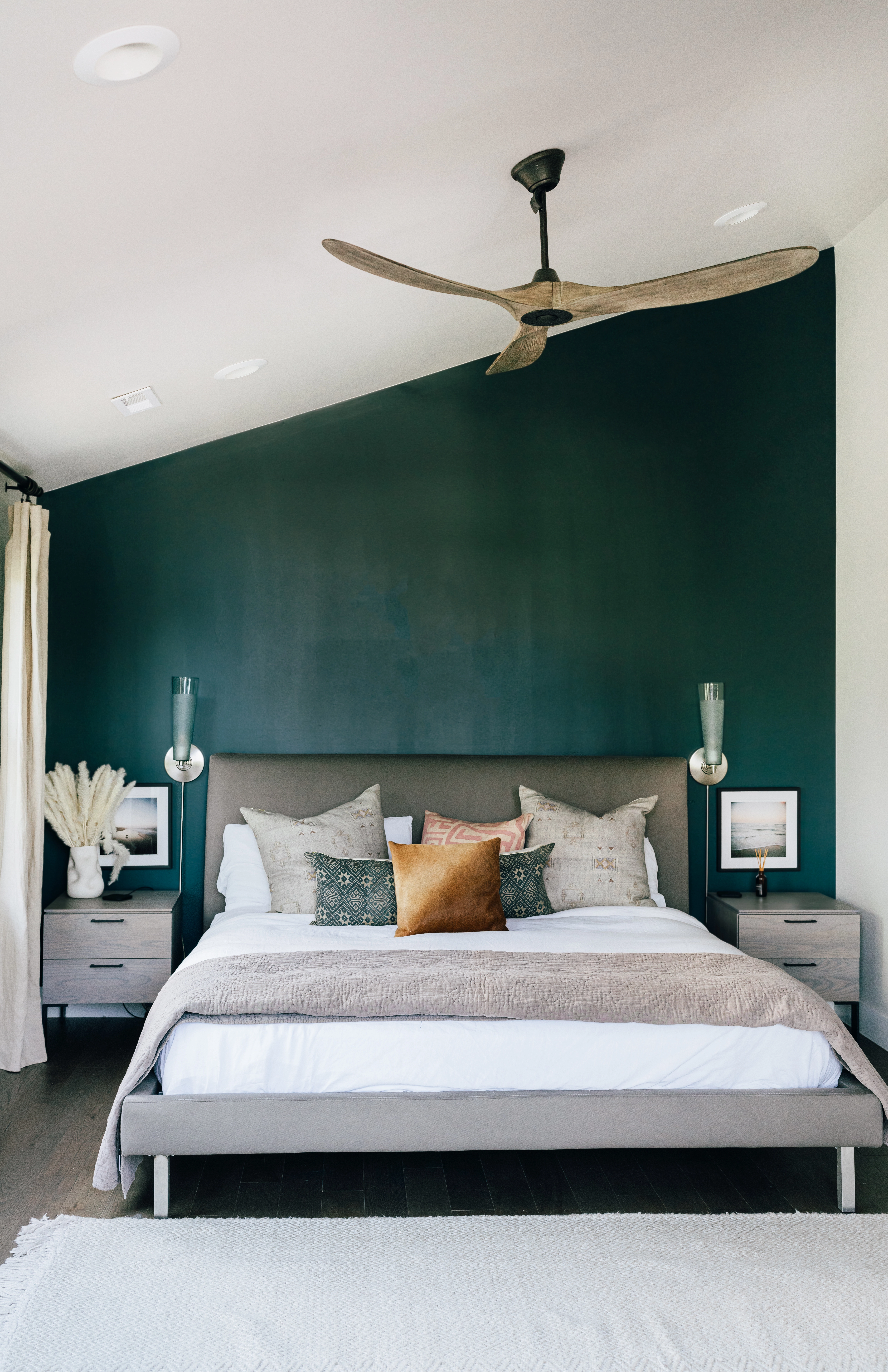 Bohemian style slanted bedroom ceiling with white walls, a forest green accent wall, and gray decor.