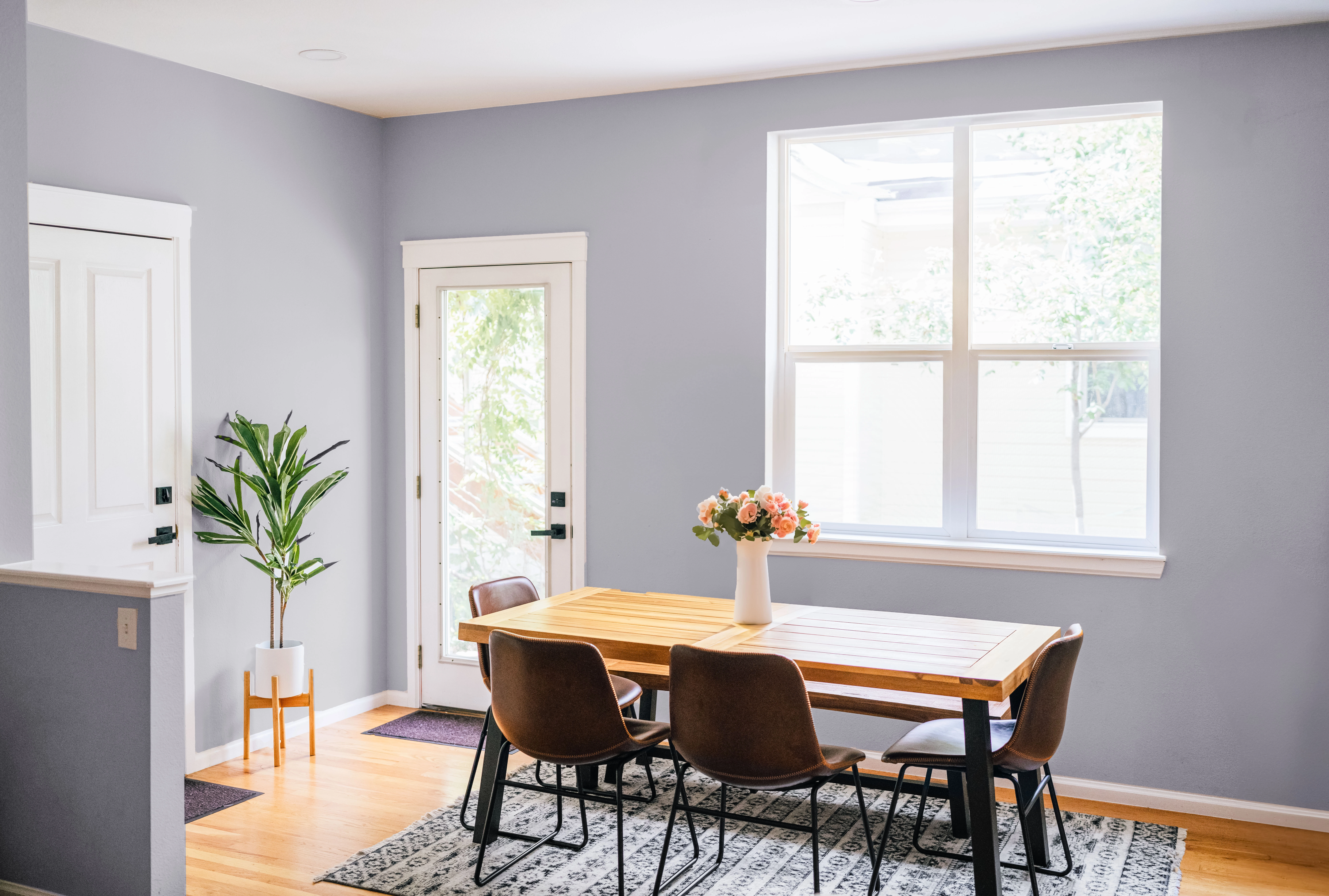 Light gray-blue painted walls and white trim inside dining room. Table and floors are light wood.