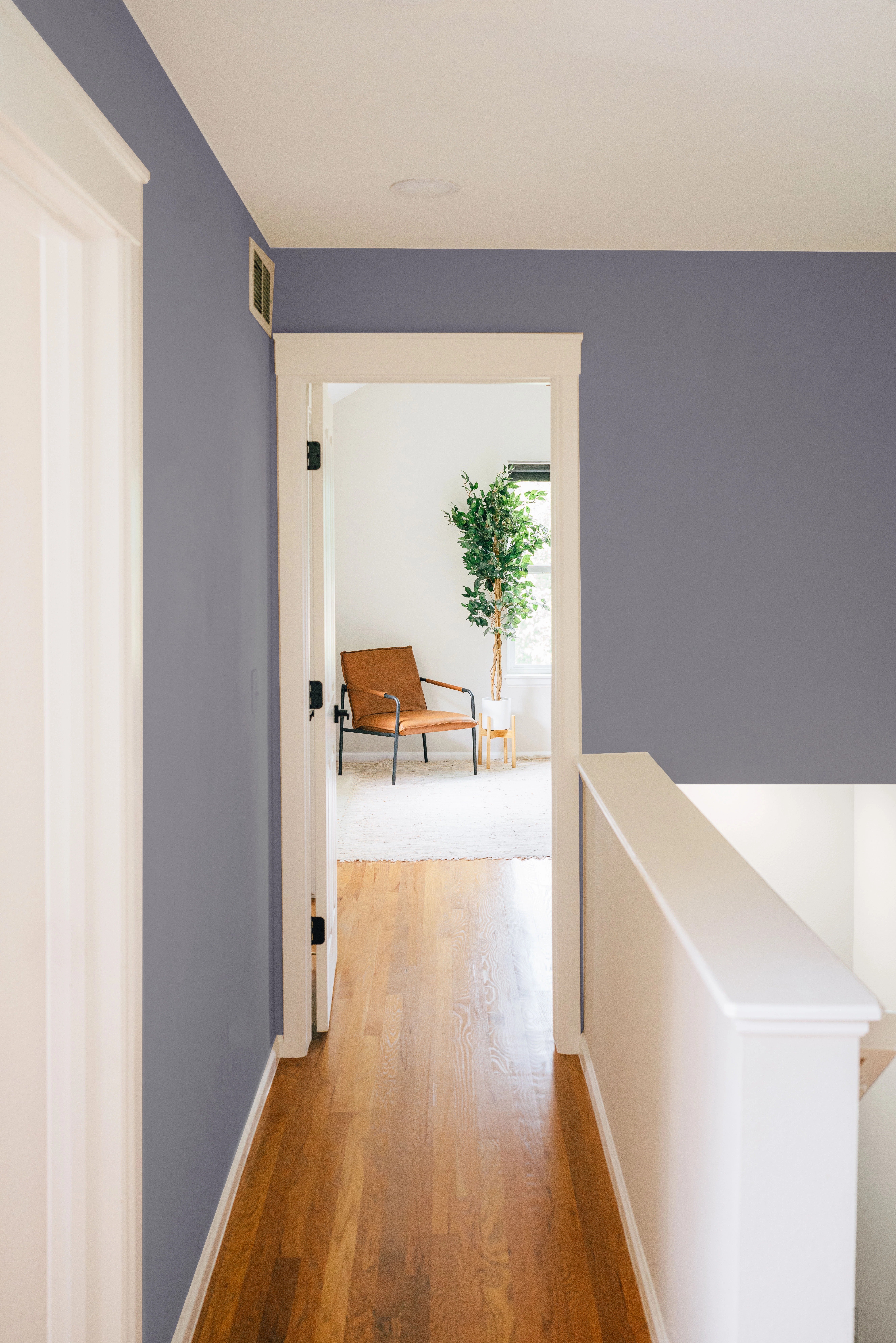 Steel blue painted hallway with white trim and doors along stairs of second floor in home. 