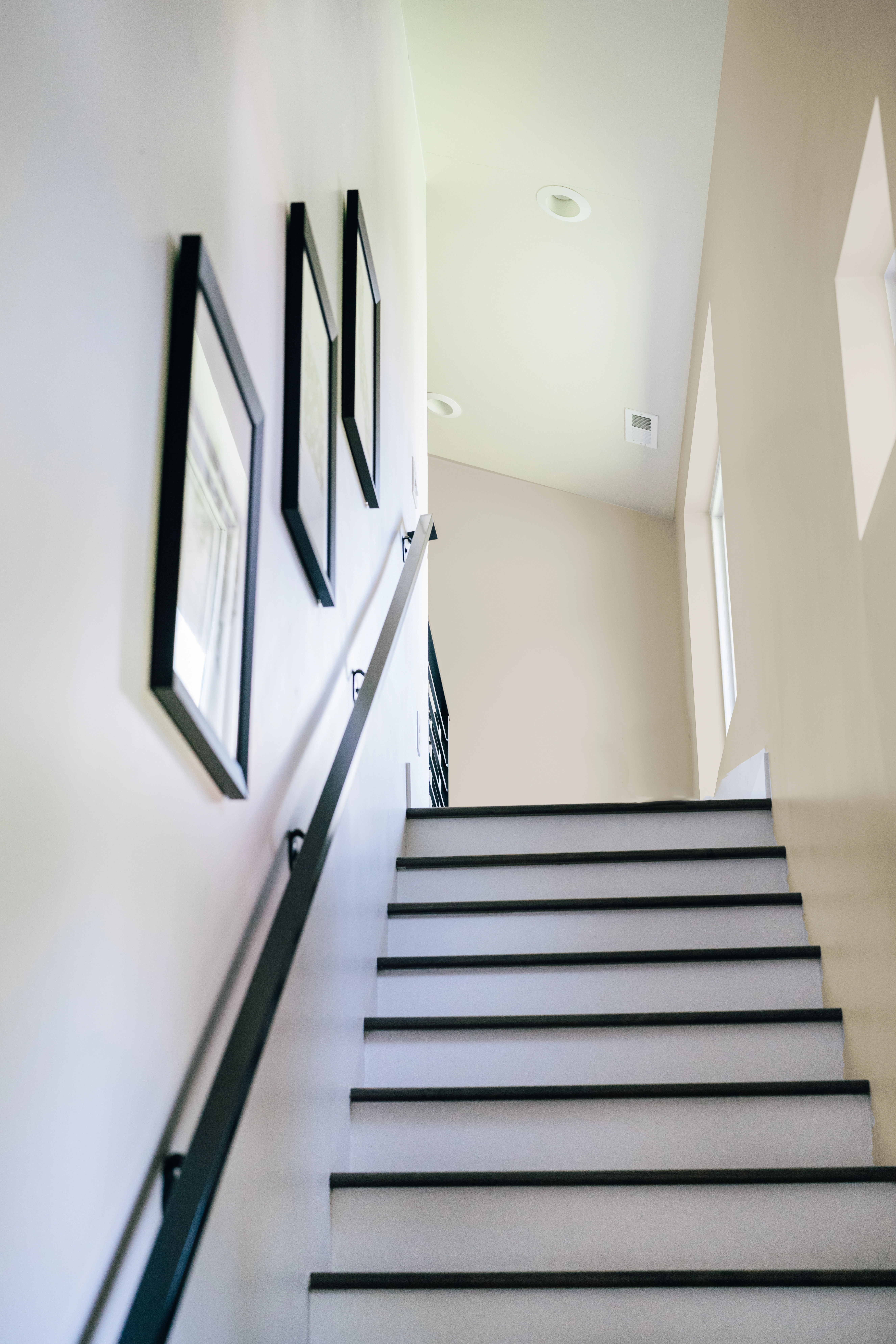 Angled view in stairway with white painted steps, black trim and railing, and beige walls.