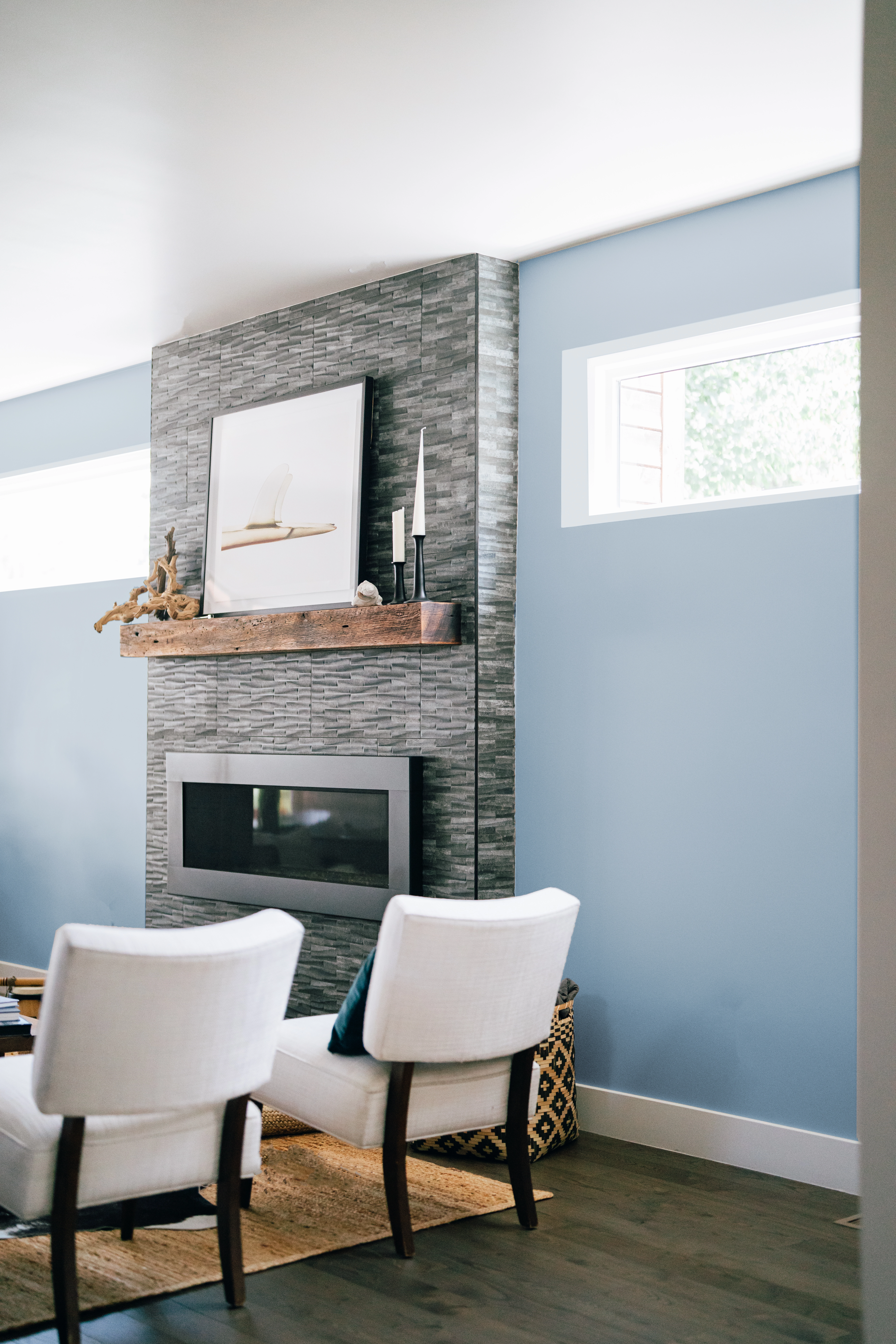 Cropped view of electric center fireplace with painted gray brick, sky blue walls, and boho decor.