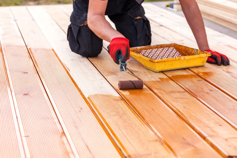 Painter staining a wooden deck.