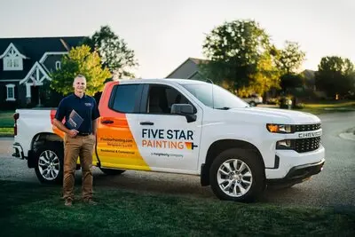 Five Star Painting estimator standing on lawn in front of white company pick up truck
