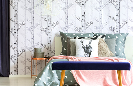 Wallpaper installation services in bedroom with bed, side table, tree wallpaper.