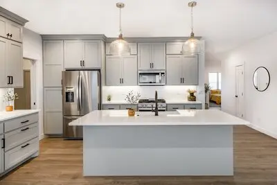 Trendy, modern farm-style kitchen with light gray cabinets, pendent lights, and kitchen island.